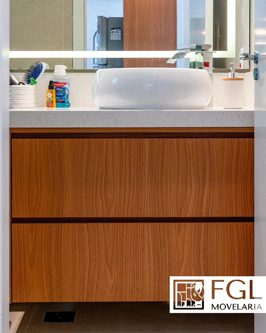 Banheiro com cuba de apoio, bancada clara e gabinete amadeirado sob medida